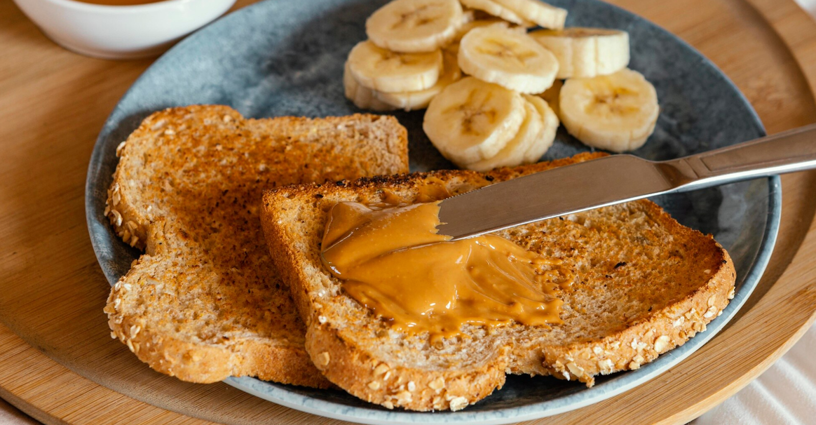 A well-composed shot of delicious, healthy toast with toppings like peanut butter, banana, and cinnamon.